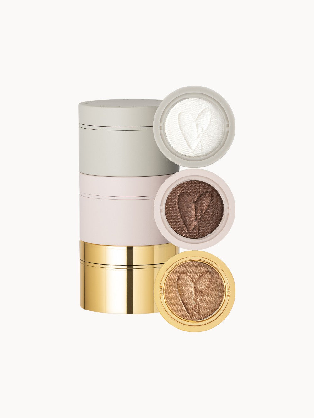 Dreiteiliges Lidschattenset in stapelbaren Dosen in Grau, Rosa und Gold mit geöffneten Deckeln, sichtbar sind schimmernde Lidschatten in Weiß, Braun und Bronze mit Herzprägung.
