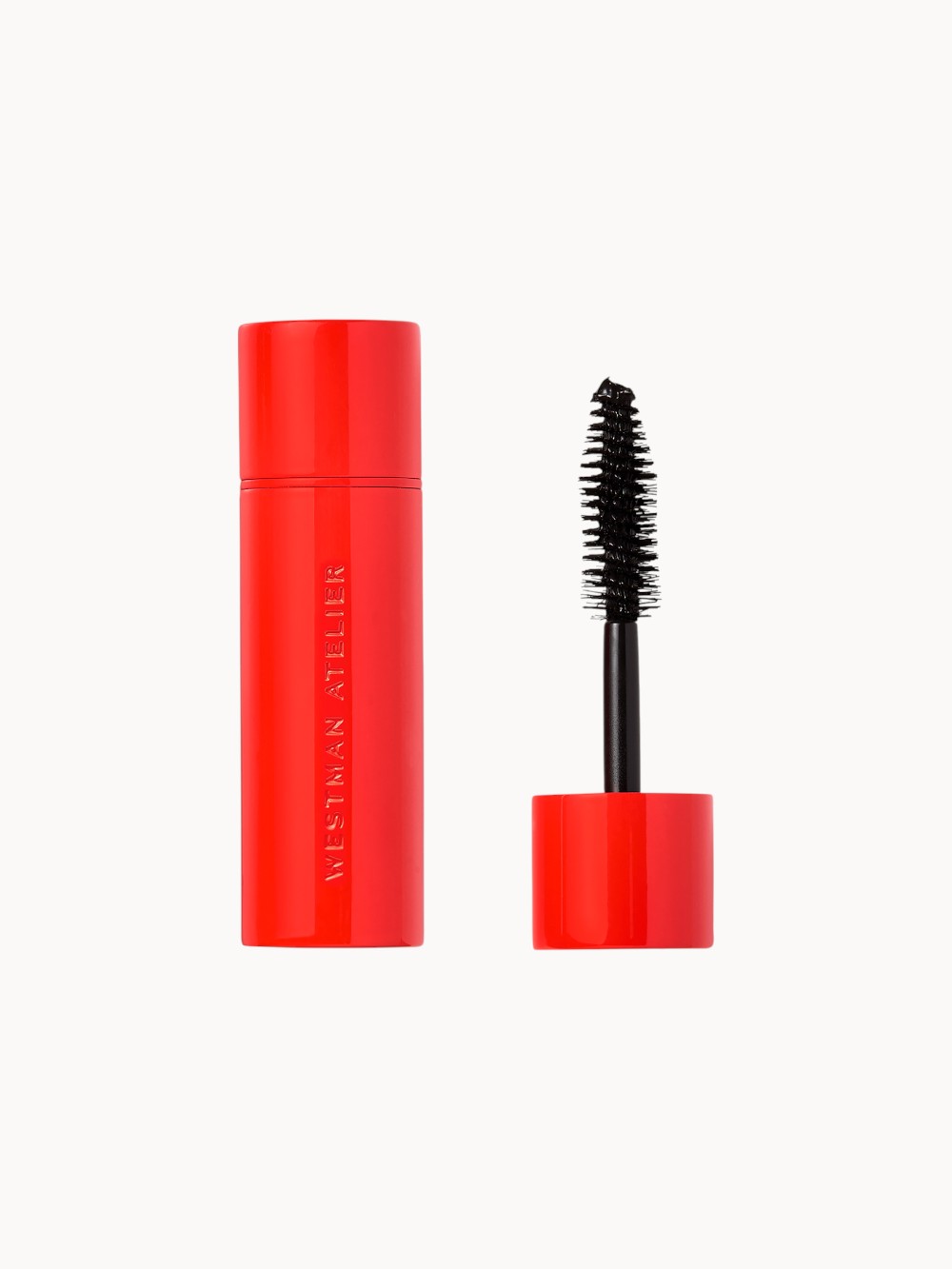 Kleine rote Mascara-Tube mit geöffneter Kappe und schwarzer, sanduhrförmiger Bürste, Produkt von Westman Atelier.