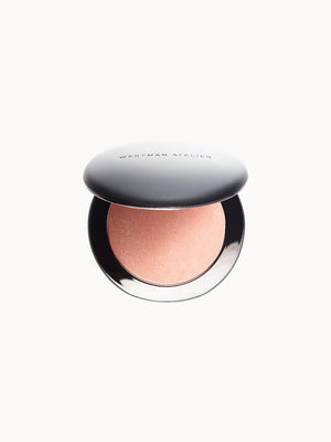 Geöffnete runde Make-up-Dose mit einem pfirsichfarbenen Highlighter, silberner Deckel mit Aufschrift „Westman Atelier“.