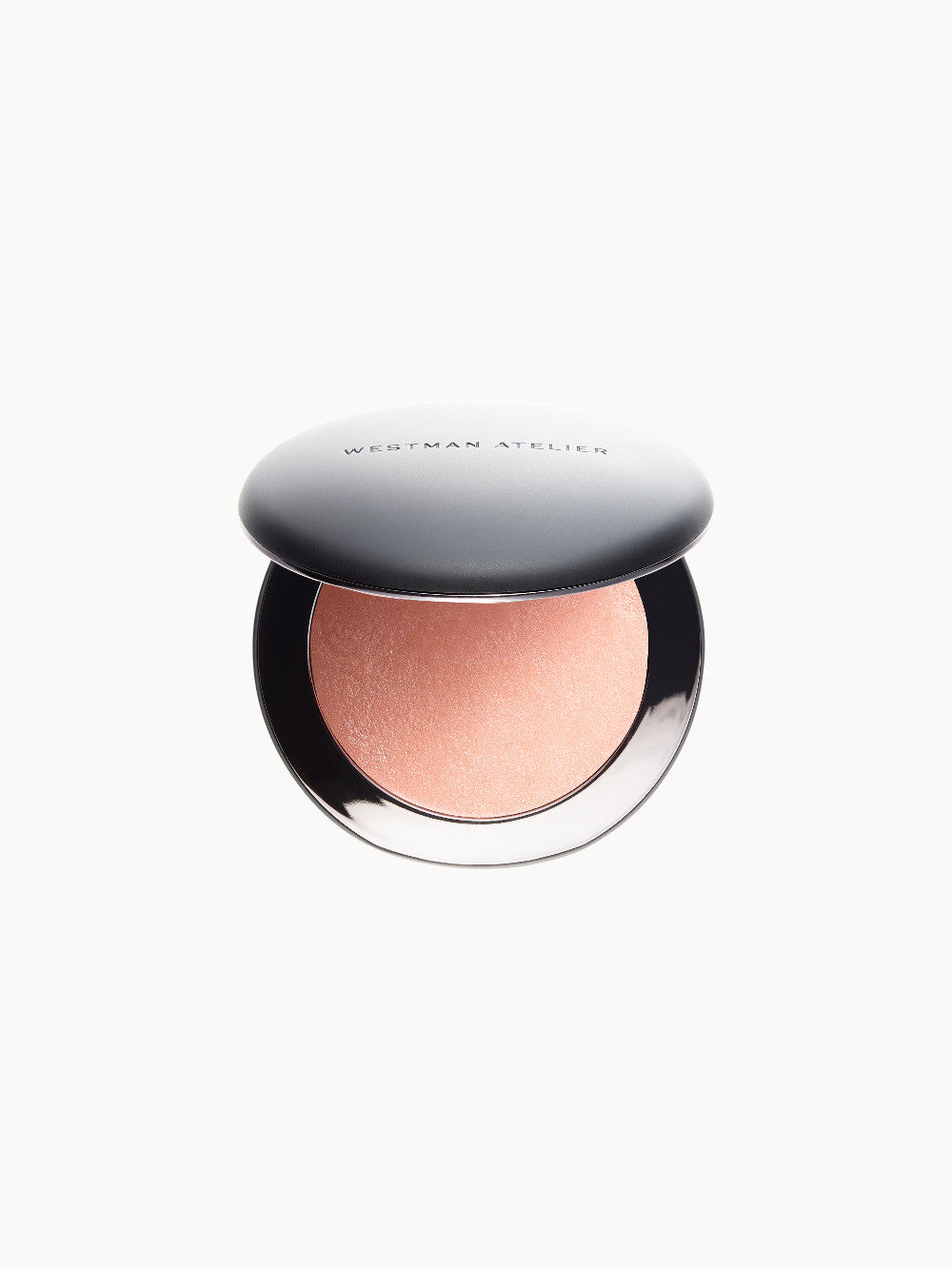 Geöffnete runde Make-up-Dose mit einem pfirsichfarbenen Highlighter, silberner Deckel mit Aufschrift „Westman Atelier“.